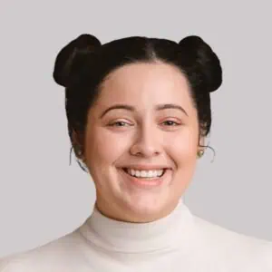Happy woman with space buns hairstyle and white turtleneck.
