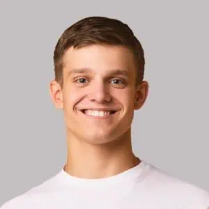 Smiling young man with short brown hair in a white shirt.